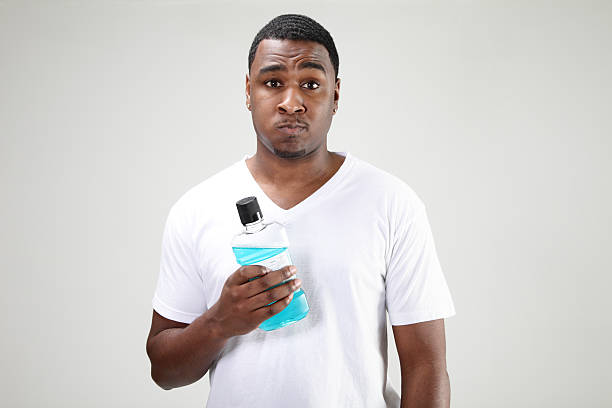 African American man using mouthwash.